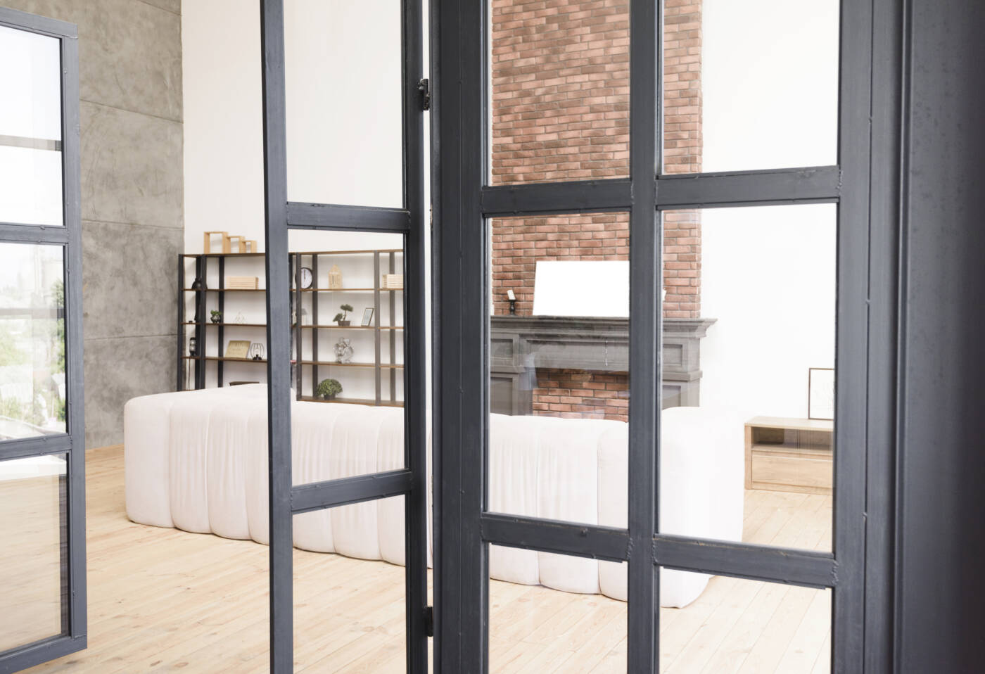 Une verrière d'intérieur en bois peint en noir qui sépare le salon de la salle à manger grâce à des portes de verrière.
